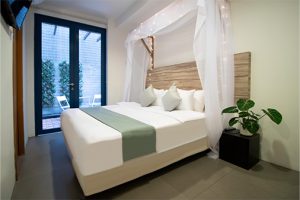 hotel room with a deluxe king canopy bed and a balcony